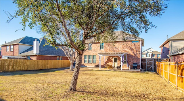 back of house with brick siding, a yard, a patio area, a pergola, and a gate