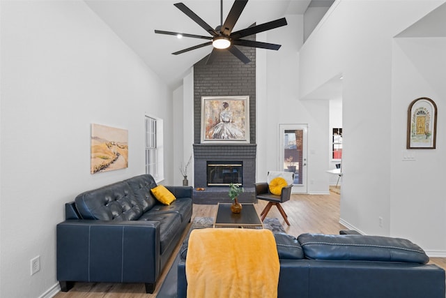 living room with a brick fireplace, ceiling fan, wood finished floors, high vaulted ceiling, and baseboards