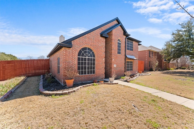 view of property exterior featuring brick siding, a yard, a chimney, and fence