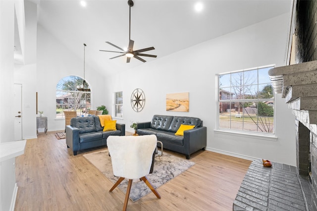 living area with baseboards, high vaulted ceiling, a fireplace, and light wood-style floors