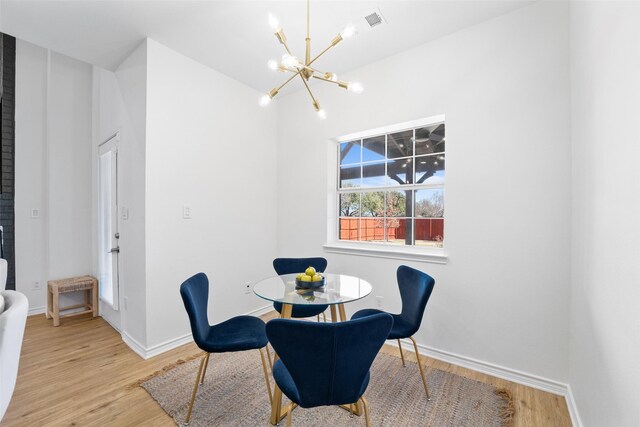 dining space featuring a chandelier, light wood-type flooring, and baseboards