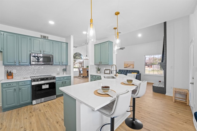 kitchen featuring visible vents, appliances with stainless steel finishes, a peninsula, light countertops, and a sink