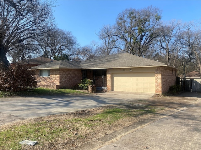 ranch-style house featuring a garage, driveway, brick siding, and fence