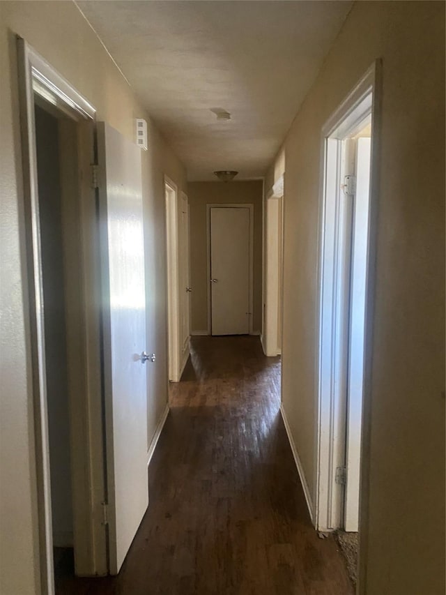 corridor with dark wood-style floors and baseboards