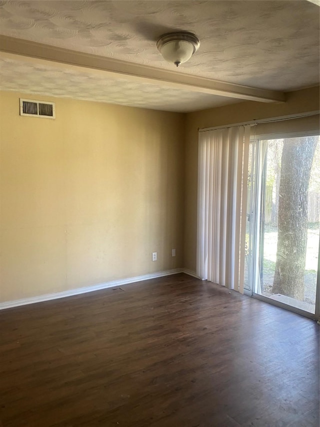 unfurnished room featuring baseboards, beam ceiling, visible vents, and dark wood-style flooring