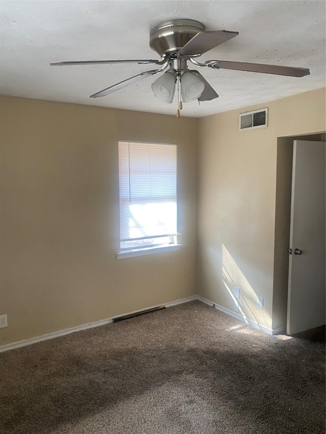 carpeted spare room featuring ceiling fan, visible vents, and baseboards