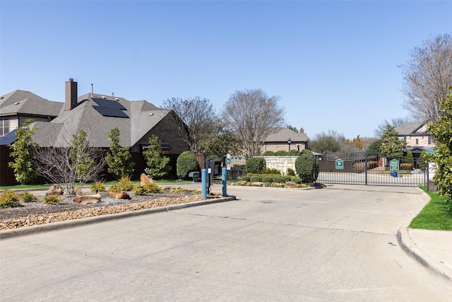 view of street with a gate, curbs, and a gated entry