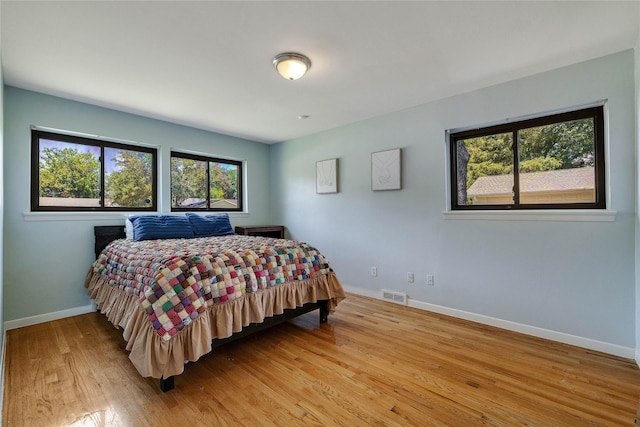 bedroom featuring wood finished floors, visible vents, and baseboards