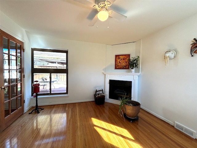 living room with wood-type flooring, a fireplace, visible vents, and baseboards