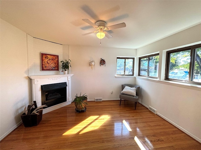 living area featuring baseboards, a fireplace, visible vents, and wood finished floors