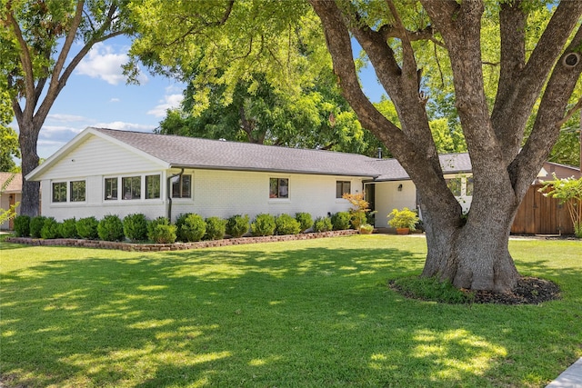 single story home with a front yard, brick siding, and fence