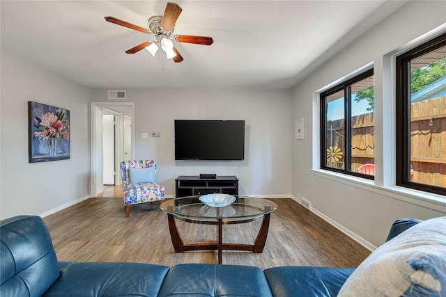 living room featuring visible vents, wood finished floors, a ceiling fan, and baseboards