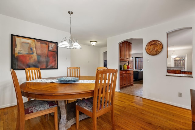 dining room with baseboards, a notable chandelier, and light wood-style floors