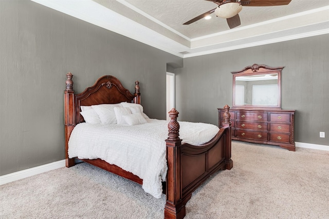 bedroom featuring baseboards, a raised ceiling, ceiling fan, crown molding, and carpet floors