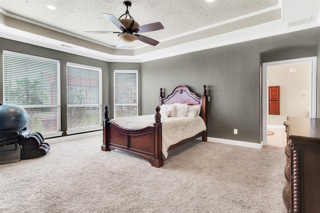 bedroom with a raised ceiling, visible vents, light colored carpet, ornamental molding, and a textured ceiling