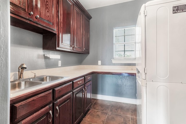 kitchen with light countertops, dark tile patterned flooring, and a sink