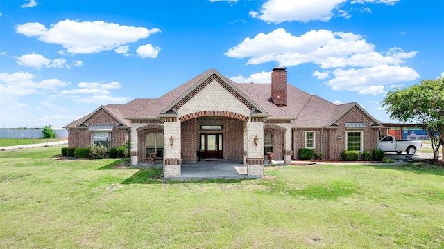 french country home featuring stone siding, brick siding, a chimney, and a front lawn