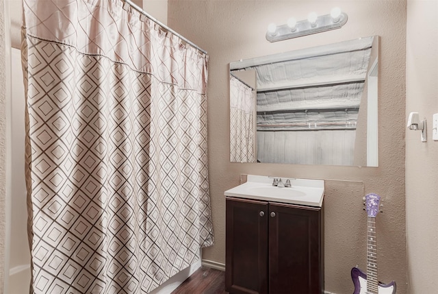 full bathroom featuring a textured wall and vanity