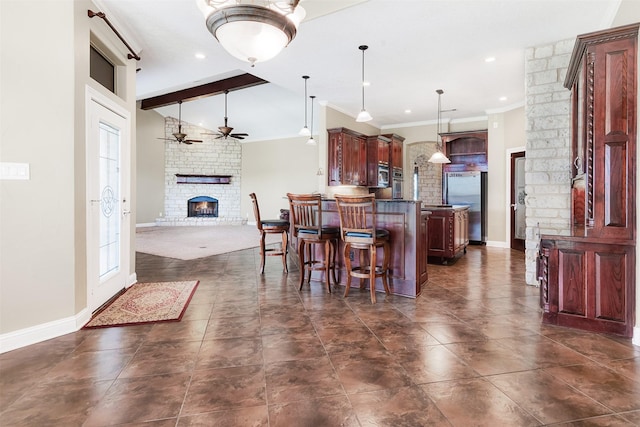 kitchen with vaulted ceiling with beams, stainless steel appliances, a fireplace, open floor plan, and dark countertops