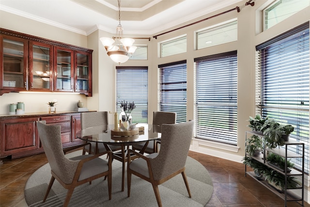 dining room featuring ornamental molding, a tray ceiling, a notable chandelier, and dark tile patterned floors