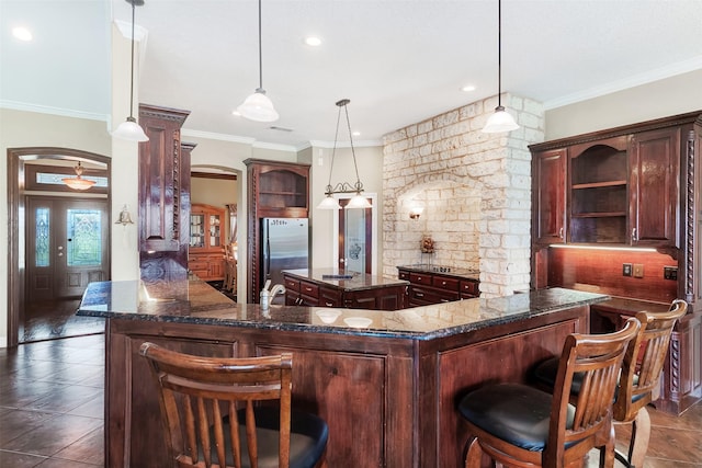 bar with arched walkways, dark tile patterned floors, hanging light fixtures, freestanding refrigerator, and crown molding