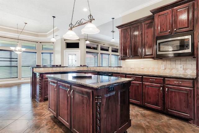 kitchen with ornamental molding, stainless steel microwave, a kitchen island, and backsplash