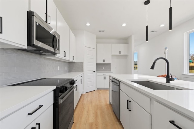 kitchen featuring light countertops, appliances with stainless steel finishes, a sink, and light wood-style floors