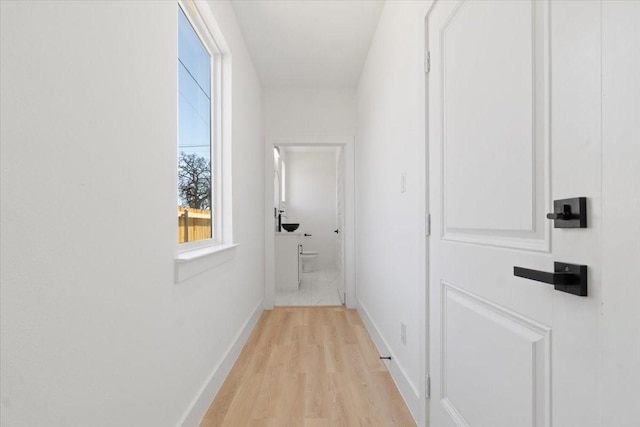 hall with baseboards and light wood finished floors