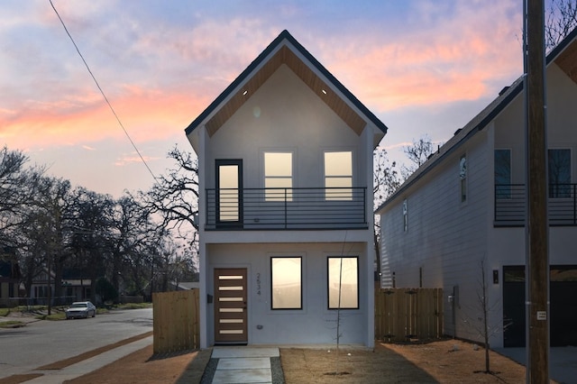 rear view of property with a balcony, fence, and stucco siding