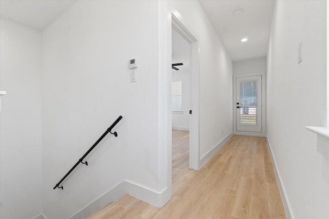 hallway featuring recessed lighting, baseboards, light wood finished floors, and an upstairs landing