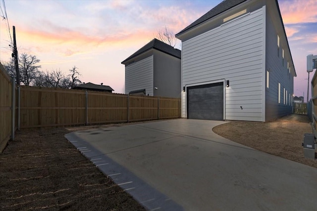 view of side of home with a garage, concrete driveway, and a fenced backyard