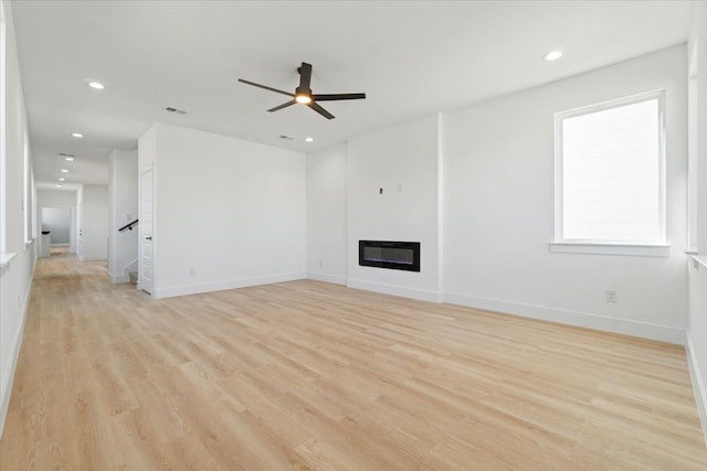 unfurnished living room with light wood-style floors, a glass covered fireplace, visible vents, and recessed lighting