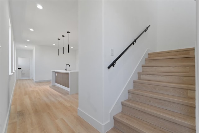 staircase with baseboards, wood finished floors, and recessed lighting