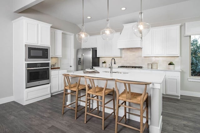 kitchen with custom exhaust hood, tasteful backsplash, light countertops, appliances with stainless steel finishes, and a sink