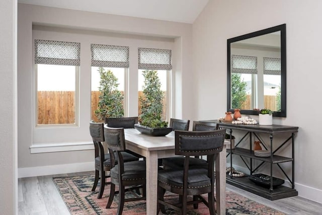 dining space featuring lofted ceiling, plenty of natural light, and wood finished floors