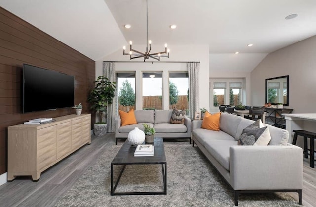 living room featuring lofted ceiling, recessed lighting, a notable chandelier, wood walls, and light wood-style floors