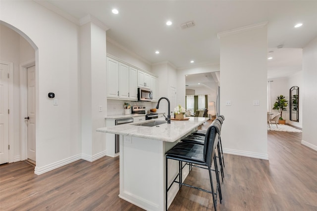 kitchen featuring stainless steel appliances, a sink, visible vents, a kitchen bar, and a center island with sink