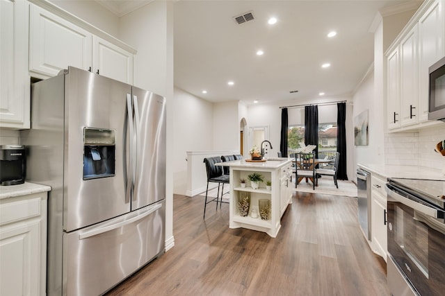 kitchen featuring visible vents, white cabinets, decorative backsplash, stainless steel appliances, and open shelves