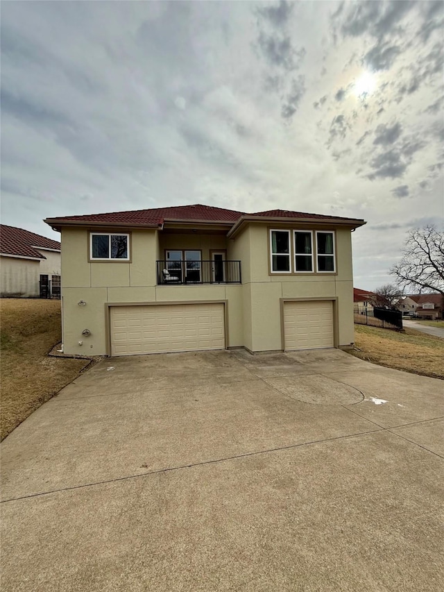 view of front facade featuring a garage, concrete driveway, a balcony, and stucco siding