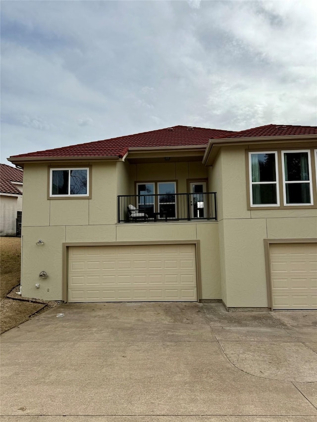 view of front of home with a balcony, an attached garage, concrete driveway, and stucco siding