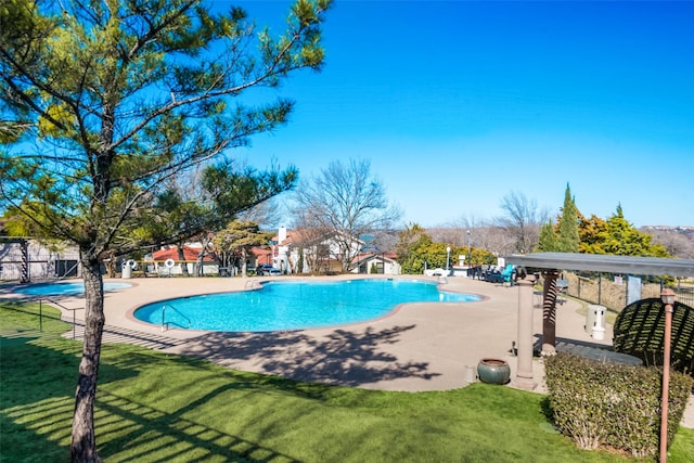 community pool featuring a patio, a lawn, and fence