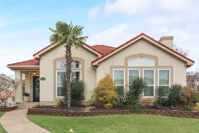 mediterranean / spanish-style home featuring a front yard, a tile roof, and stucco siding