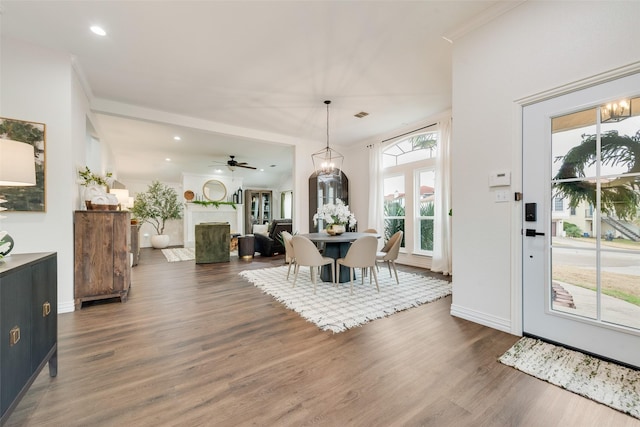 dining space featuring recessed lighting, baseboards, wood finished floors, a fireplace, and ceiling fan with notable chandelier