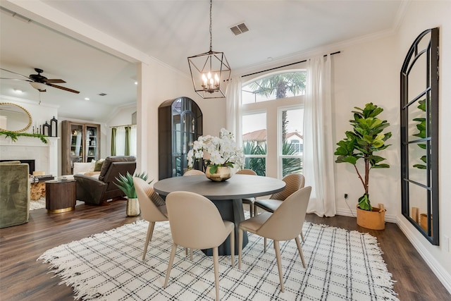 dining space featuring crown molding, dark wood finished floors, a fireplace, visible vents, and baseboards