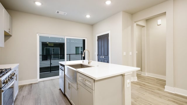 kitchen featuring stainless steel appliances, recessed lighting, visible vents, a sink, and light wood-type flooring