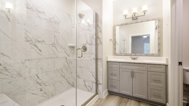 bathroom with toilet, a stall shower, wood finished floors, and vanity