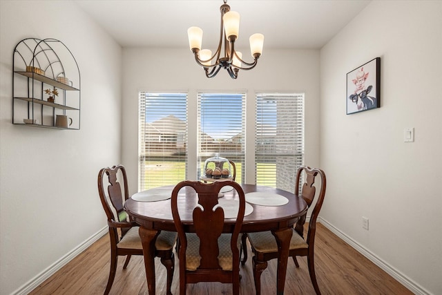 dining space featuring a chandelier, light wood-type flooring, and baseboards