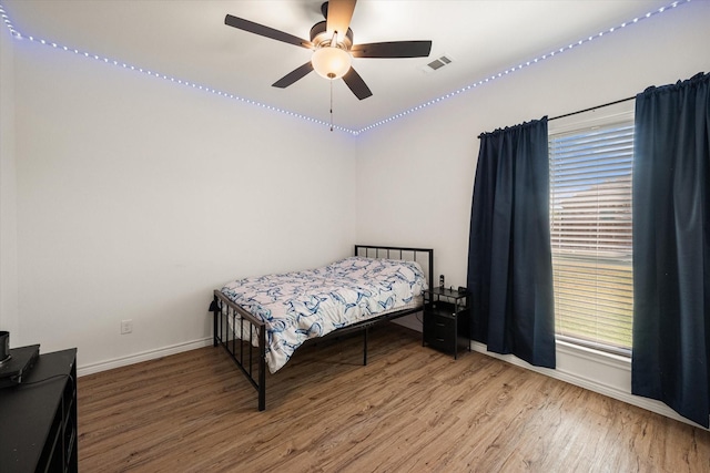 bedroom featuring baseboards, visible vents, ceiling fan, and wood finished floors