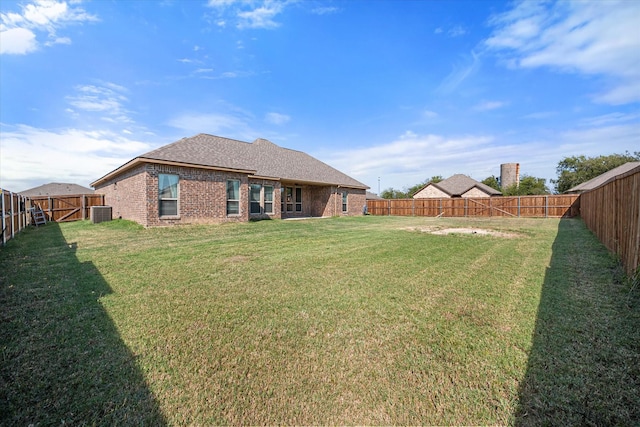 back of house with brick siding, roof with shingles, a lawn, a gate, and a fenced backyard