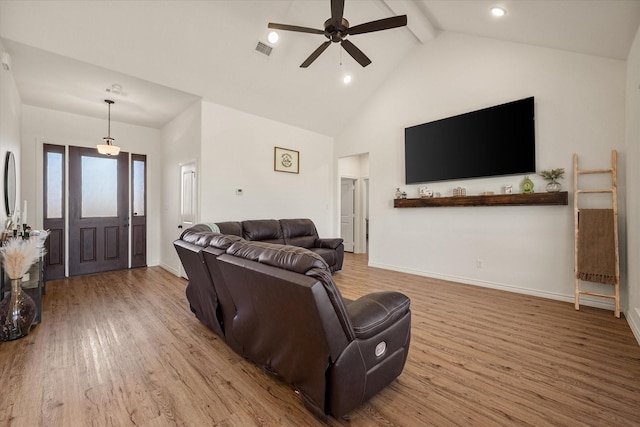 living room with high vaulted ceiling, wood finished floors, visible vents, and baseboards